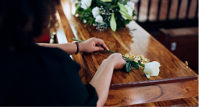 woman laying rose on coffin