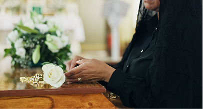 women laying white rose on coffin